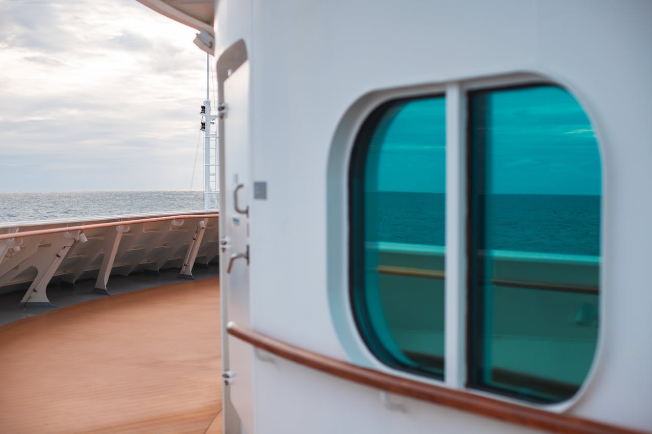 Peaceful view from a cruise ship deck with ocean reflection through a green window.